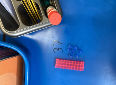 Dienes blocks on a blue table with the numbers they represent written next to them.